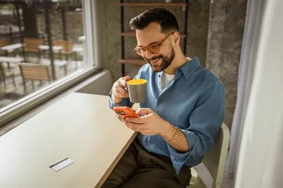 Homem usando um smartphone e cartão de crédito para fazer compras online em um café
